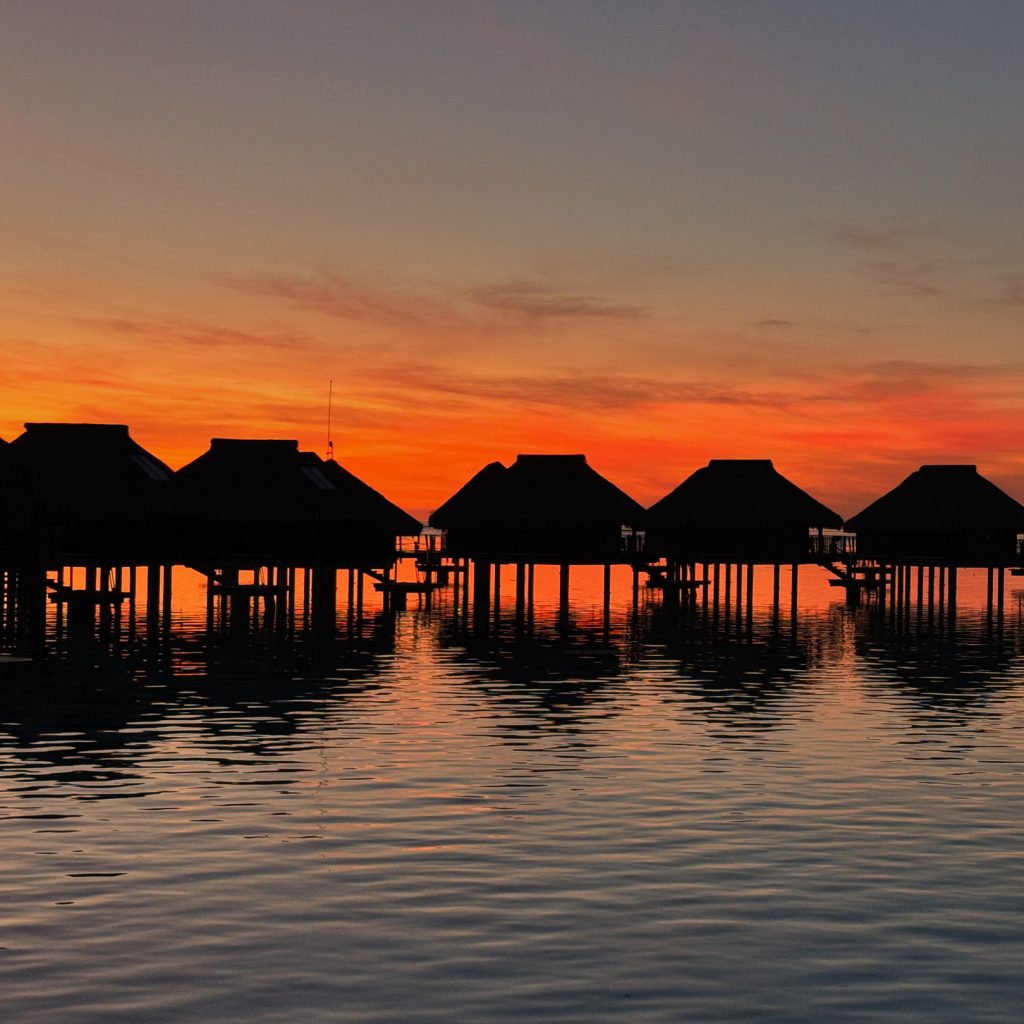 The silhouette of overwater bungalows in sunrise at Hilton Moorea Lagoon Resort and Spa, Moorea, French Polynesia
