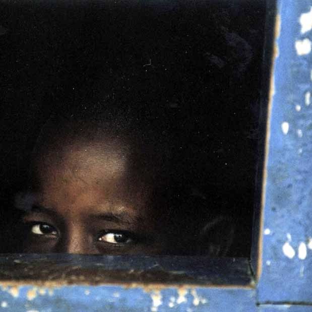 An African boy peeking out of the blue window, Kenya
