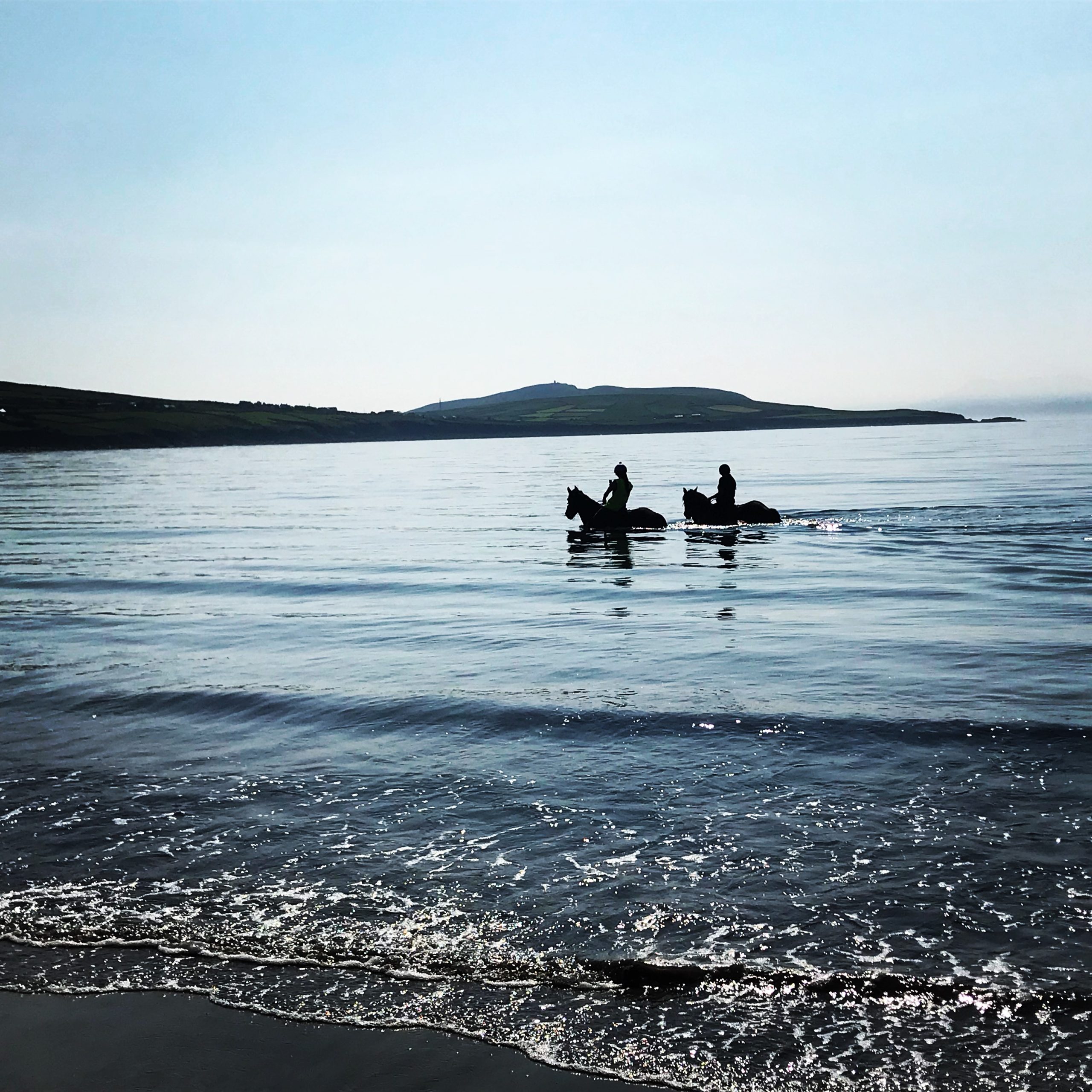 Two people riding horse on Ventry Beach, Ireland Two people riding horse on Ventry Beach, Ireland
