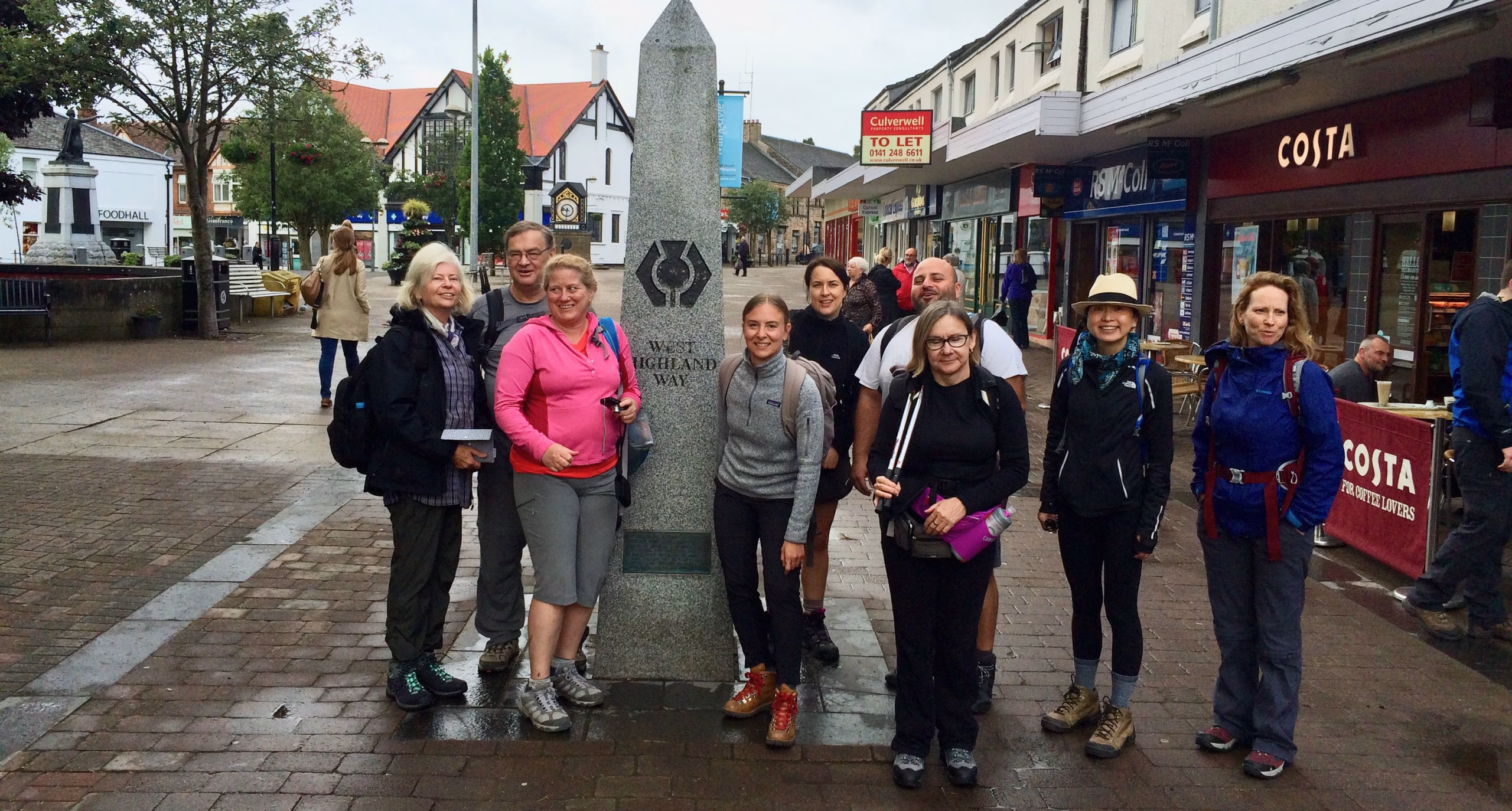 hikers gather around the West Highland Way obelisk at Milngavie town center