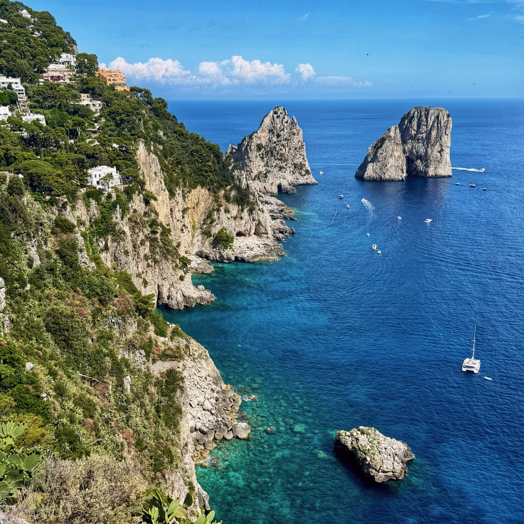 Dramatic view from the Gardens of Augustus, showing Capri’s rugged cliffs, turquoise waters, and the iconic Faraglioni rock formations in the distance