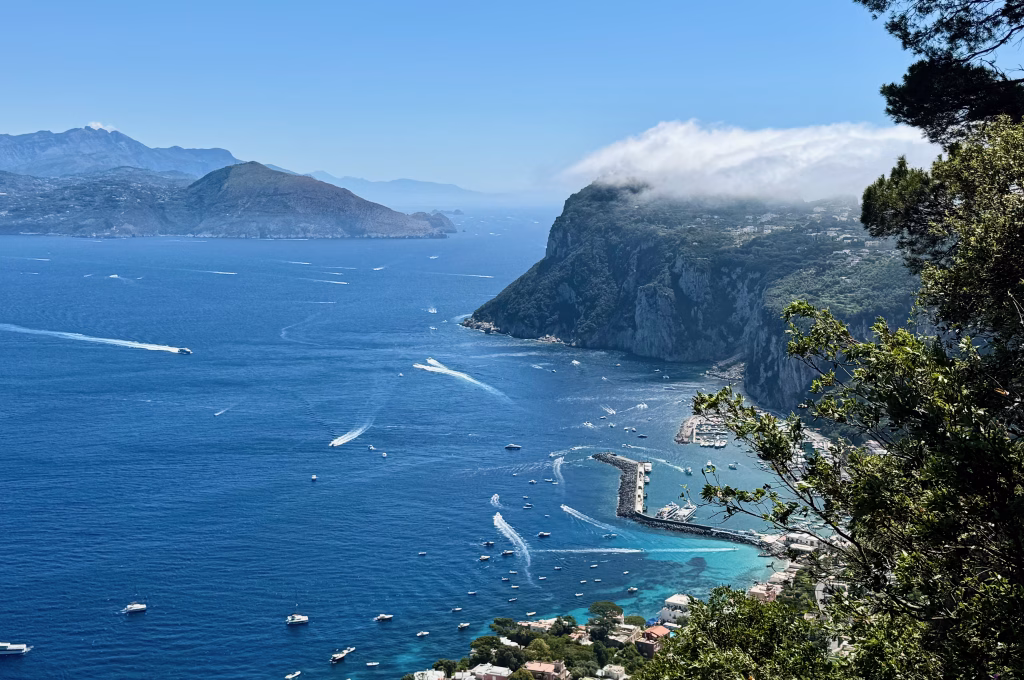 View from the Phoenician Steps overlooking Marina Grande, Capri’s harbor, with boats scattered over turquoise waters and mist hugging the cliffs
